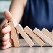 Businesswoman hand Stopping Falling wooden Dominoes. Business, Risk Management, Solution and strategy Concepts