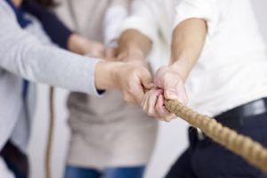 39597443 - group of businesspeople playing tug-of-war, focus on hands.