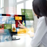 business, people, technology and mass media concept - close up of woman pointing finger to news application on computer monitor in office